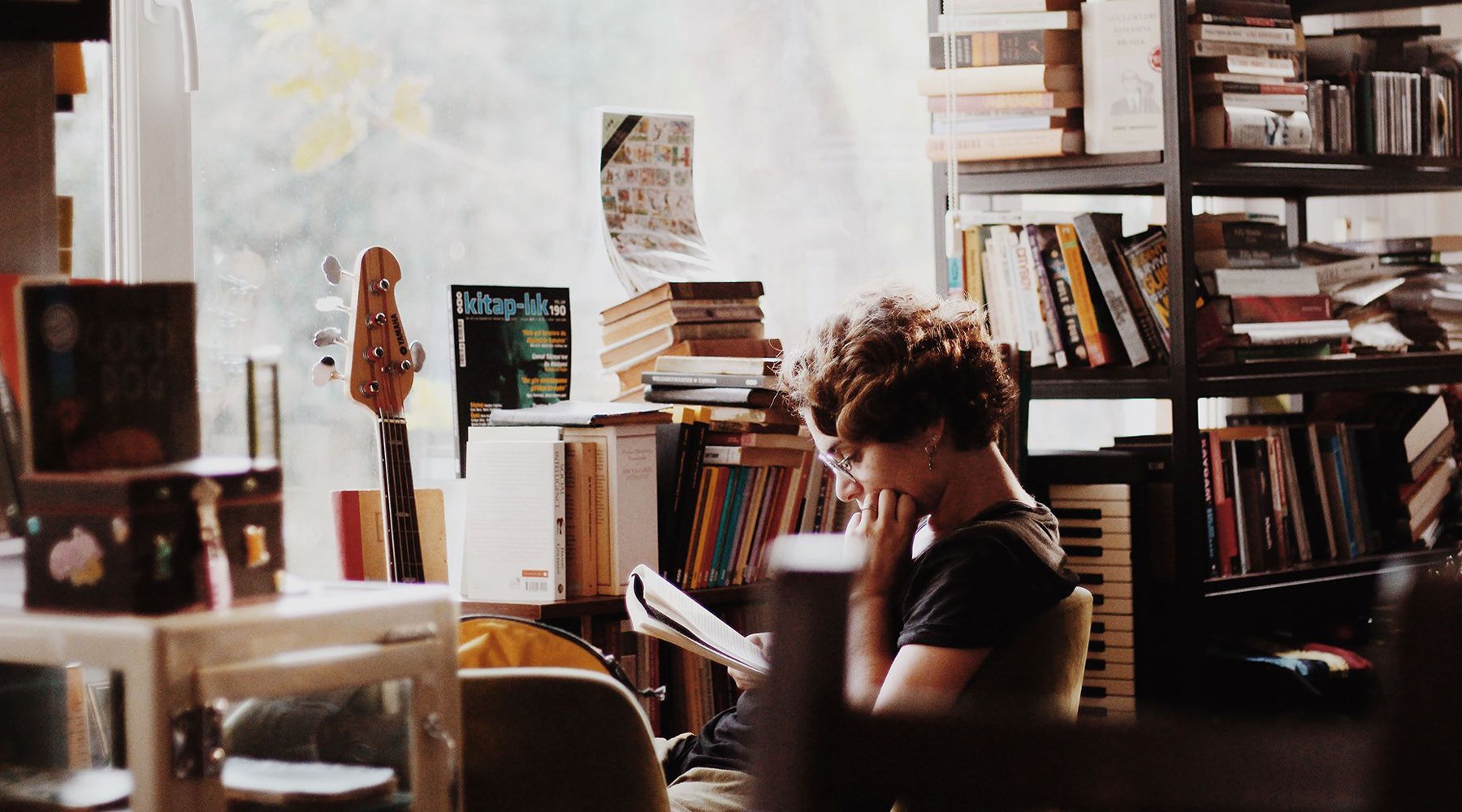 a woman reading a book near a window